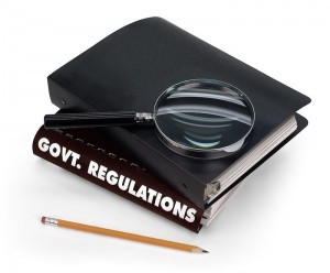 A magnifying glass on top of a book with black binding that reades "Govt. Regulations" Basics of Individual Mandate