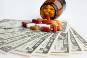 A perscription bottle with pills falling out onto various bills of 1 and 5 denominations. Learn more about the False Claims Act in Healthcare