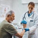 Senior patient having medical examination of at orthopedist office.