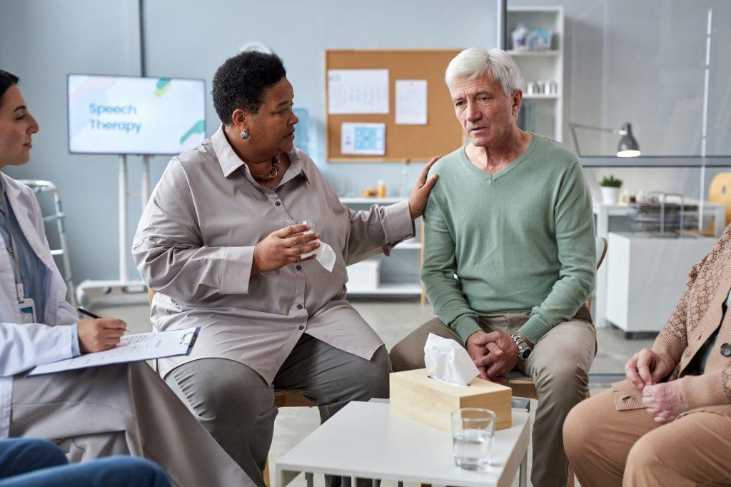 Senior white haired man sharing feelings in mental health support group