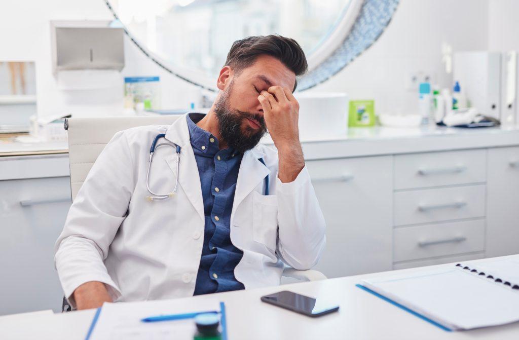 The tired doctor is sitting at the desk