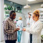 Woman pharmacist talking with a senior patient customer in a pharmacy