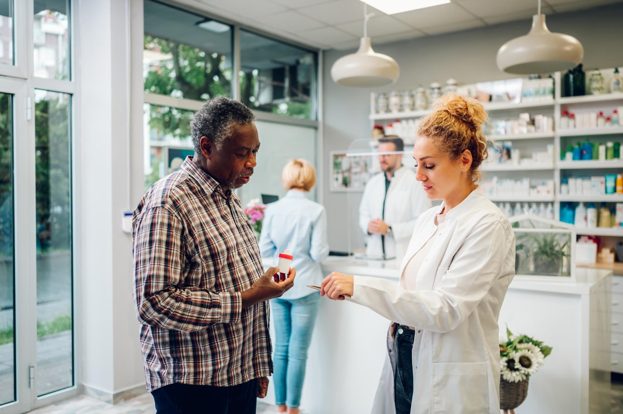 Woman pharmacist talking with a senior patient customer in a pharmacy