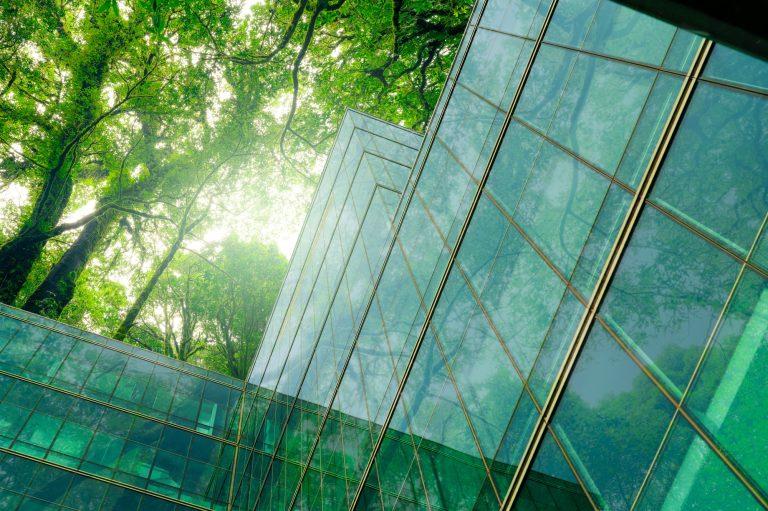 Eco-friendly building in modern city. Sustainable glass office building with trees for reducing CO2.