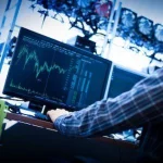 Man sitting in front of his computer, analyzing trends in data.