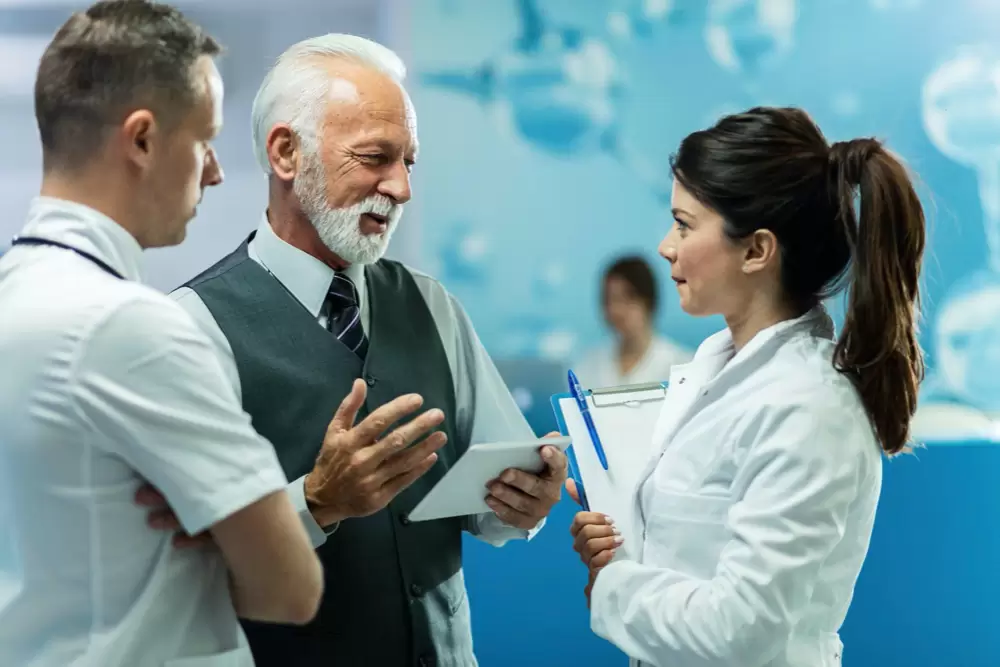A white-coated doctor having a conversation with two business persons.