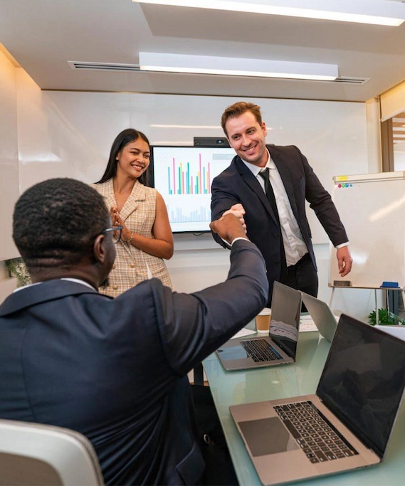 Two men coming to an agreement by fist bumping while a women smiles at them.